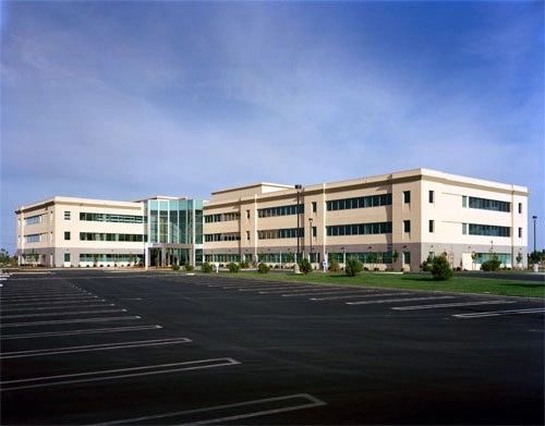 A large building with many windows and a parking lot.