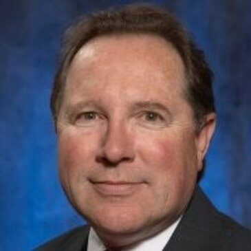 A man in suit and tie with blue background